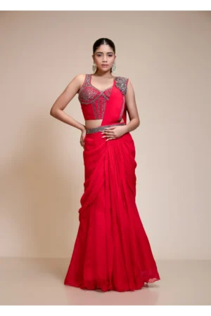 Model showcasing a red drape saree with an embroidered corset blouse featuring sequins and beadwork, paired with striking jewelry.