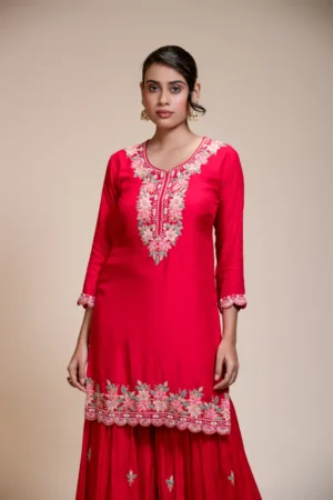 Close-up of rani pink kurta with floral embroidered round neckline, three-quarter sleeves, and embroidered hem detail