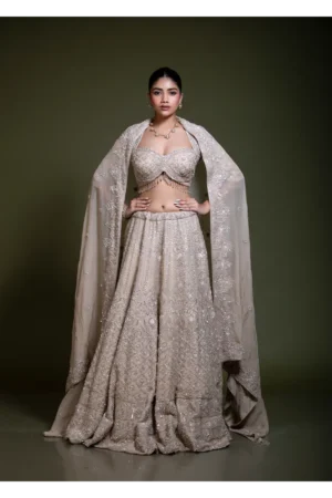 Model wearing a mocha embroidered lehenga set with sweetheart neckline blouse, heavily embellished skirt, and matching embroidered dupatta, front view